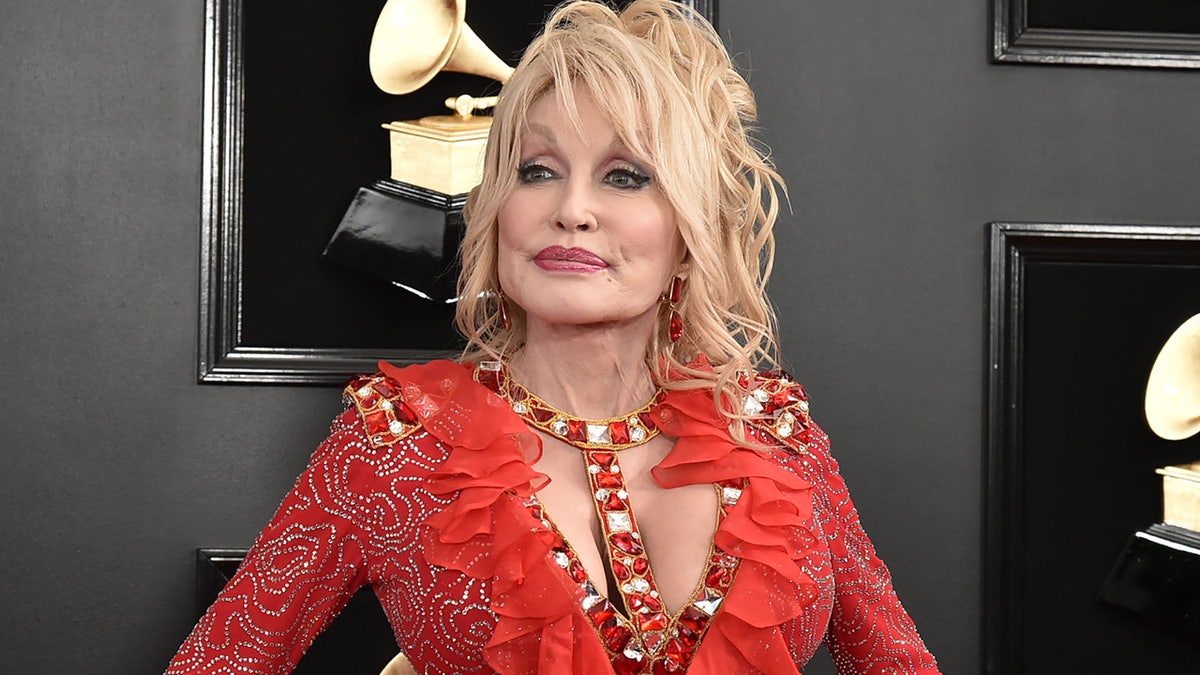 Dolly Parton in a red ruffled and sparkly dress with a bejeweled neck line at the Grammys