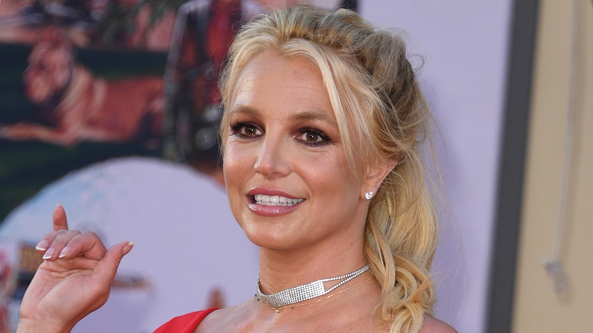 Britney Spears in a red dress and silver choker on the red carpet