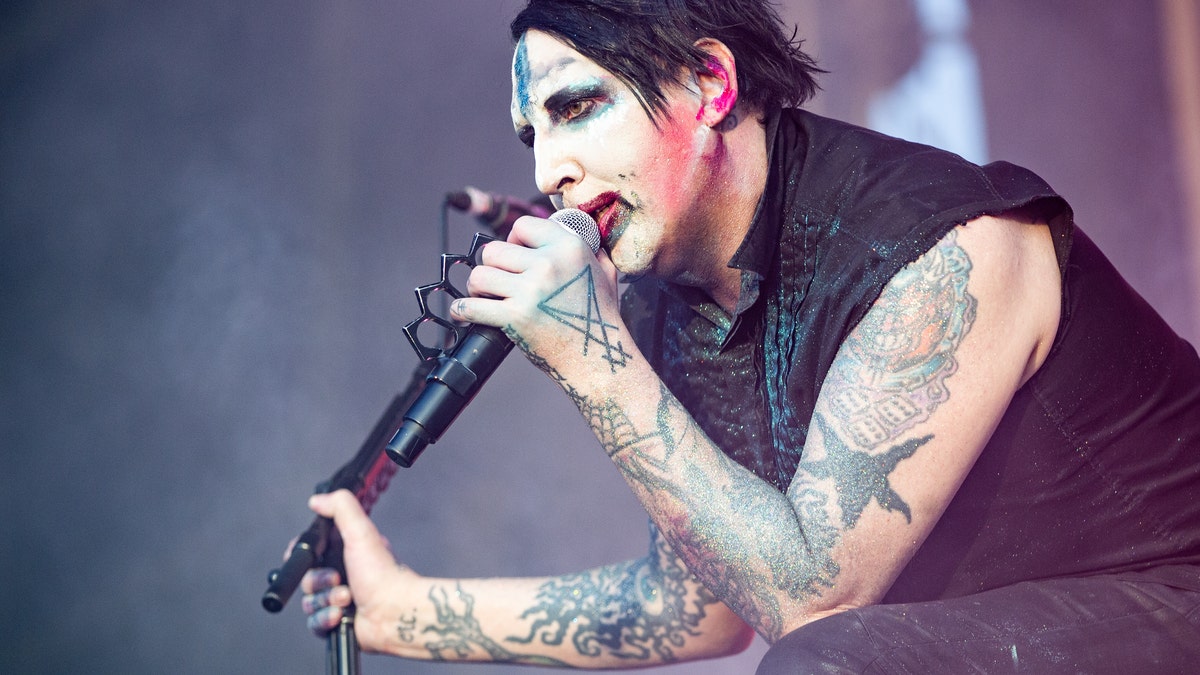 Marilyn Manson holds a microphone while performing on stage