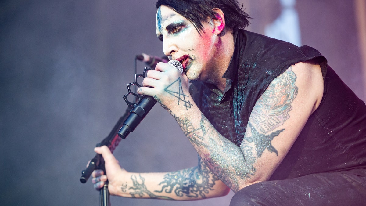 Marilyn Manson holds a microphone while performing on stage