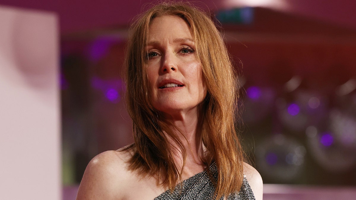 Julianne Moore looks off in the distance while wearing a sparkly one shoulder dress in Venice, Italy