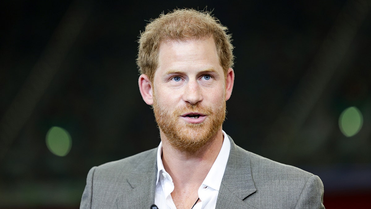 Prince Harry looks off camera in a white button down shirt and grey suit at the Invictus Games in Germany