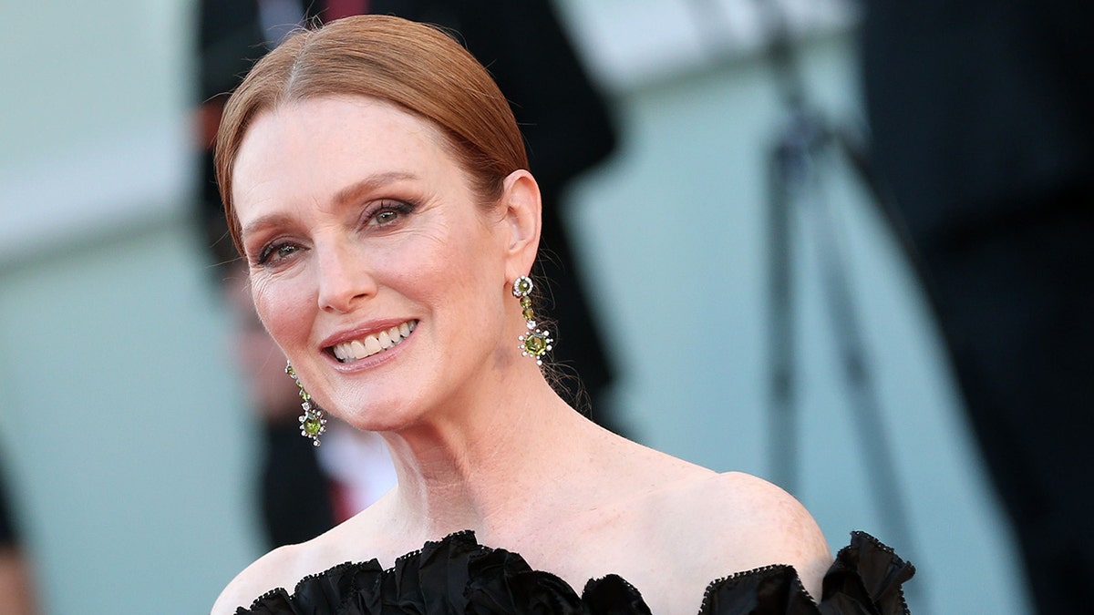 Julianne Moore with her hair pulled back on the red carpet in a black dress in Venice, Italy