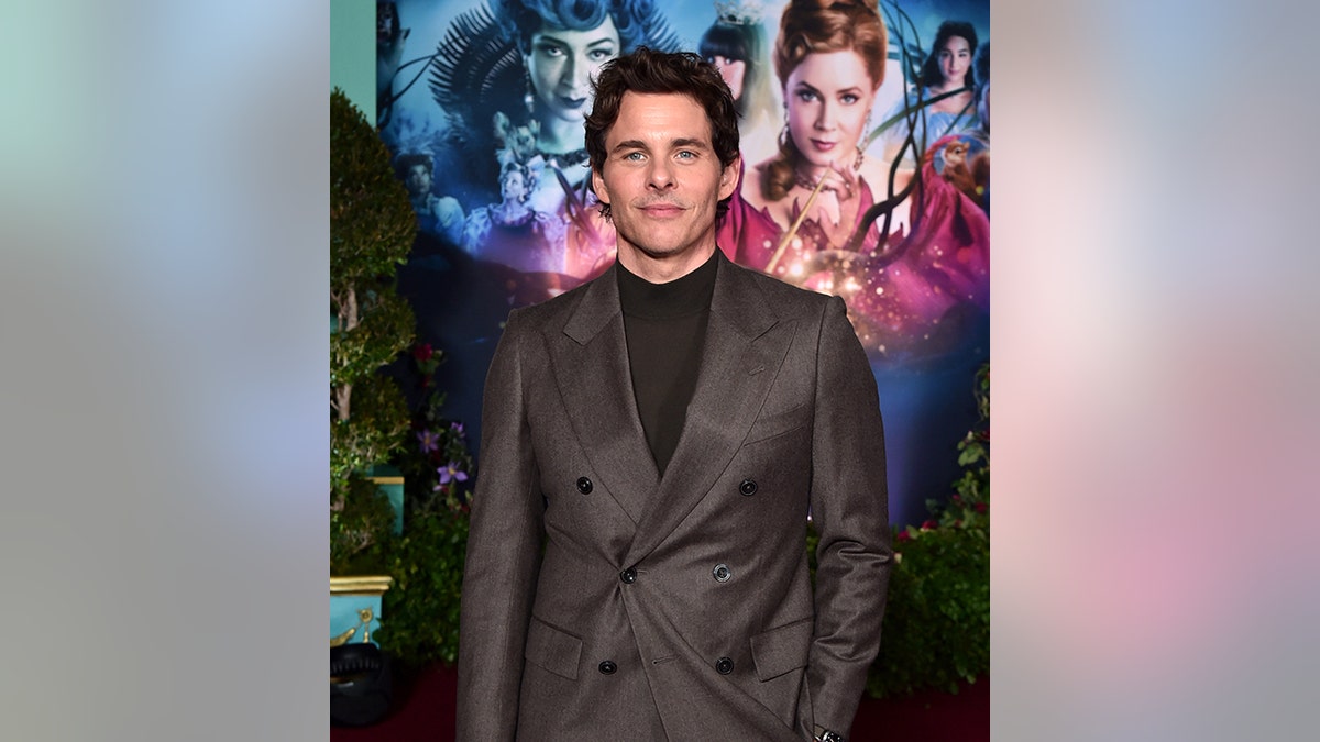 James Marsden in a black shirt and dark gray suit on the "Disenchanted" carpet