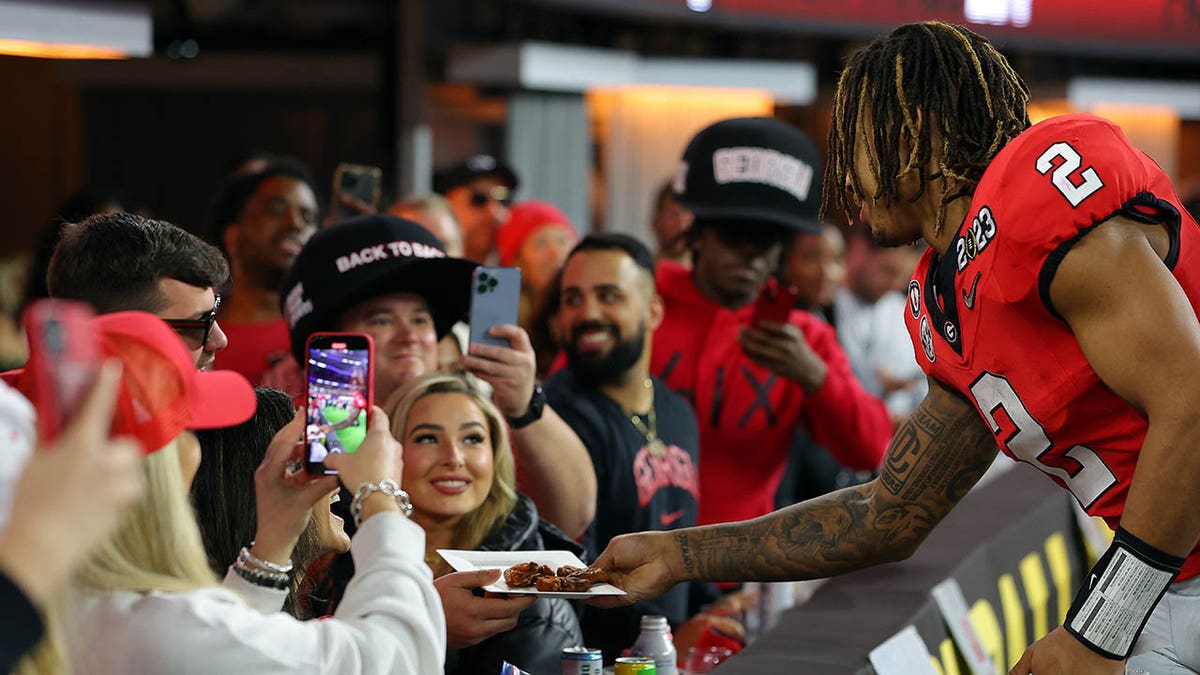Kendall Milton takes a plate of food from fans during the national championship game
