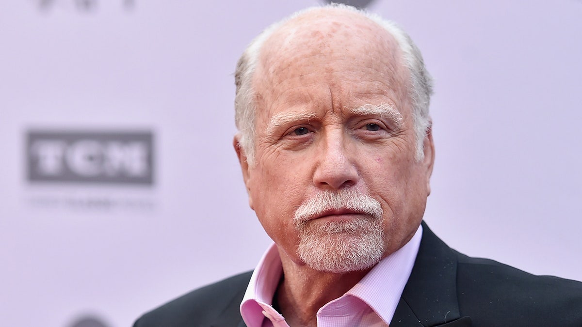 Richard Dreyfuss on the red carpet with a light pink shirt and dark suit