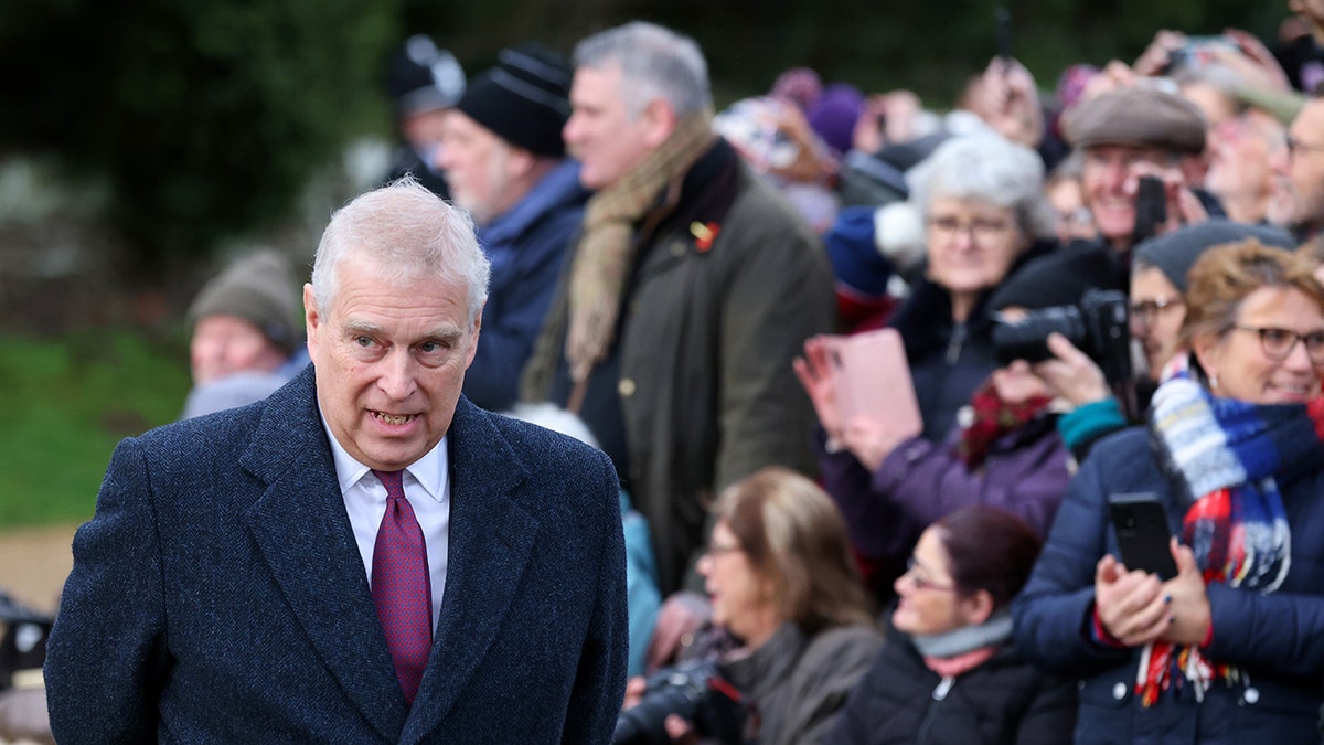 Prince Andrew looking down while in the middle of a crowd