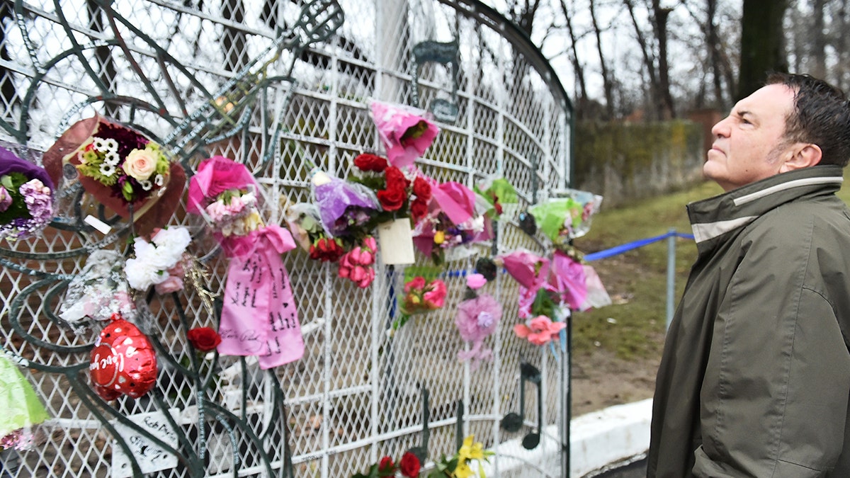 A guest placing flowers on the gates of Graceland