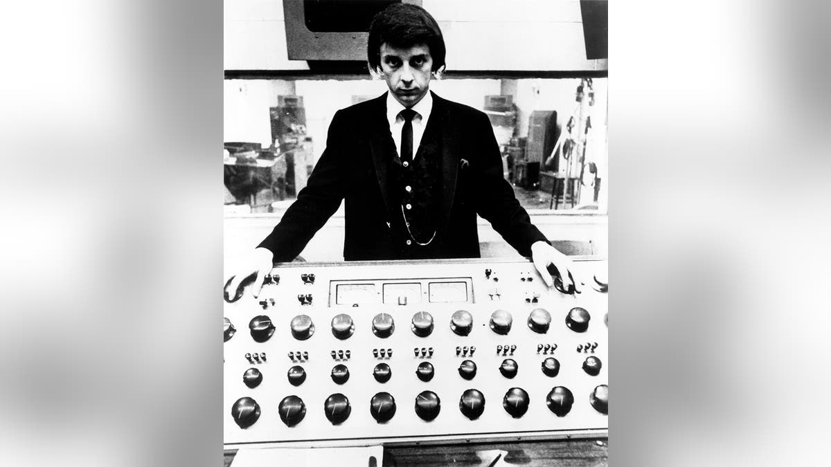 Producer Phil Spector poses at the mixing board during a recording session