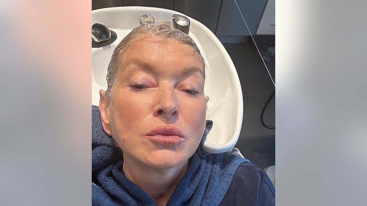 Close up photo of Martha Stewart mid-wash at hair salon posing for a selfie