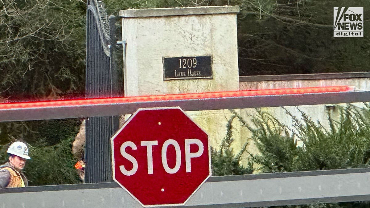 Stop sign in front of a gate in front of a fence