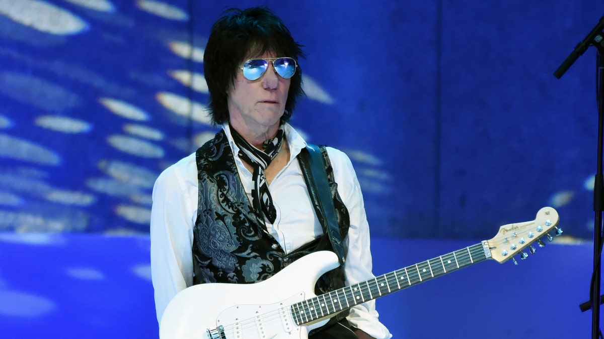Jeff Beck holds guitar at concert