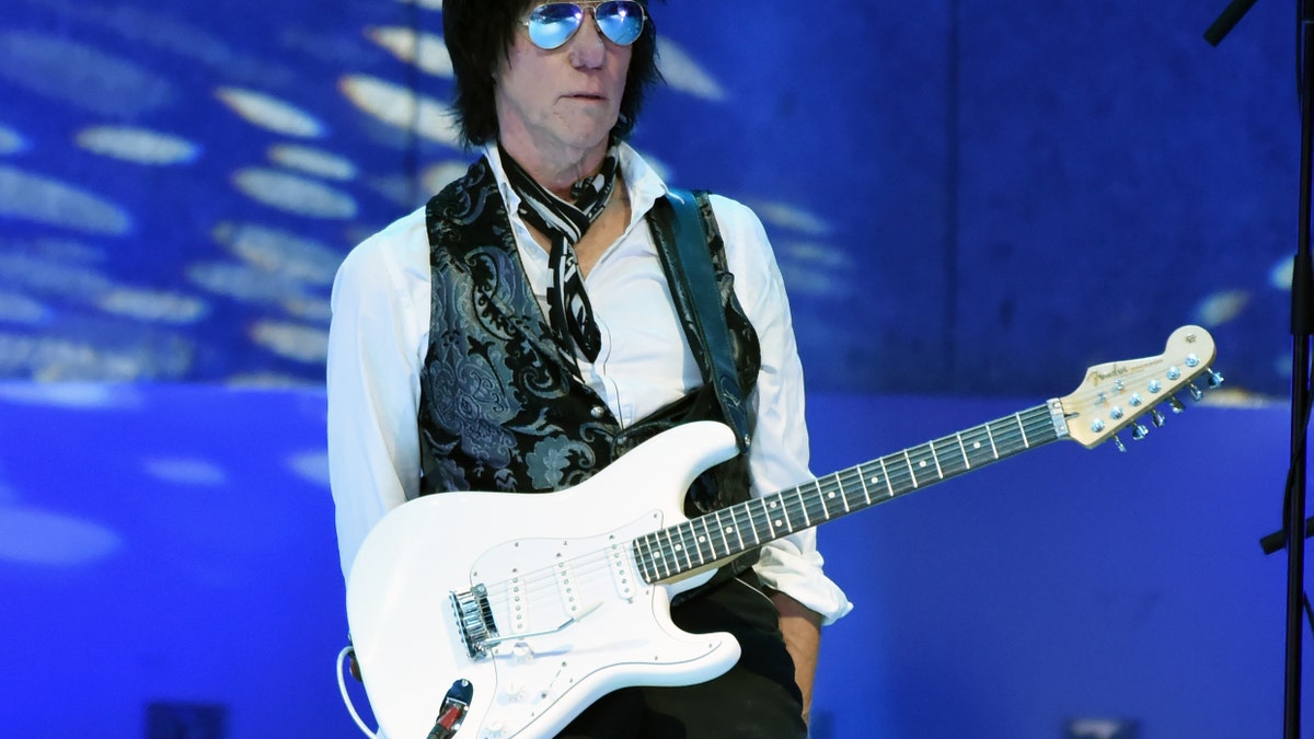 Jeff Beck holds guitar at concert