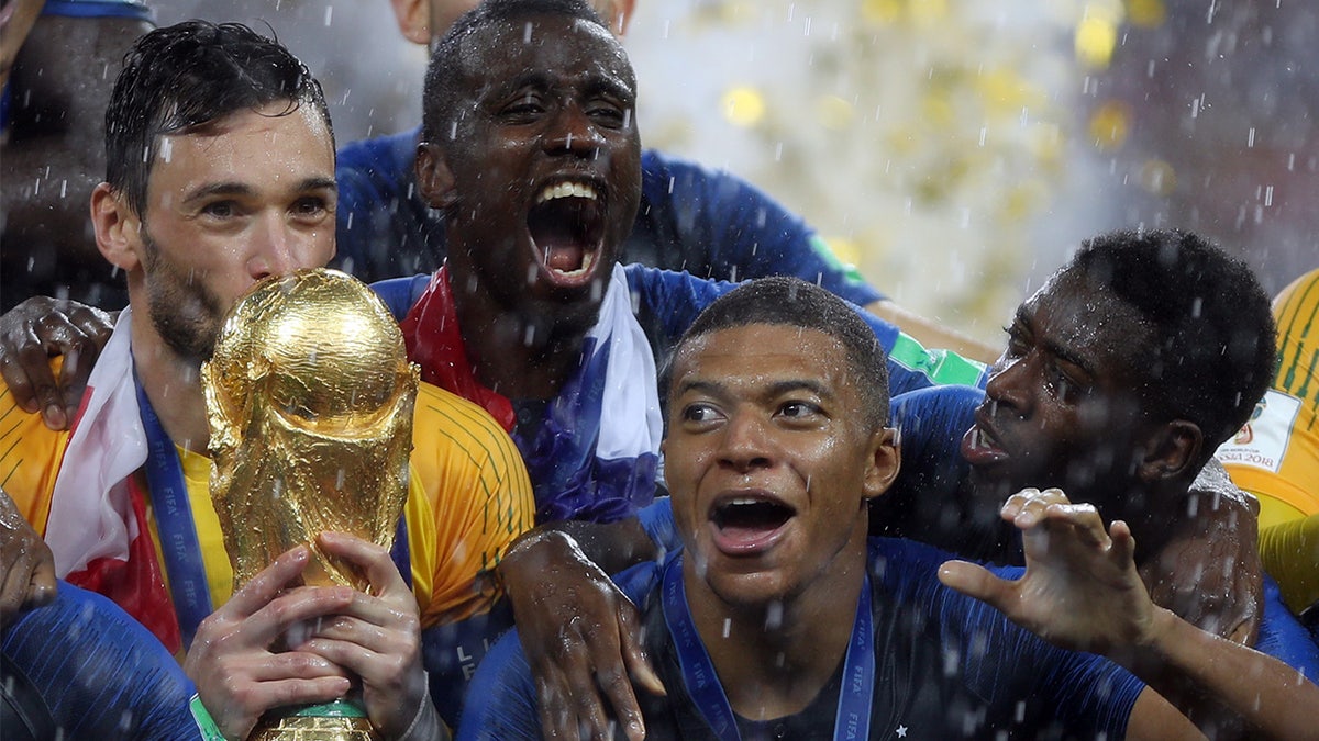 Hugo Lloris surrounded by his France teammates and holding the World Cup trophy after besting Croatia at the Luzhniki Stadium in Moscow on July 15, 2018. 