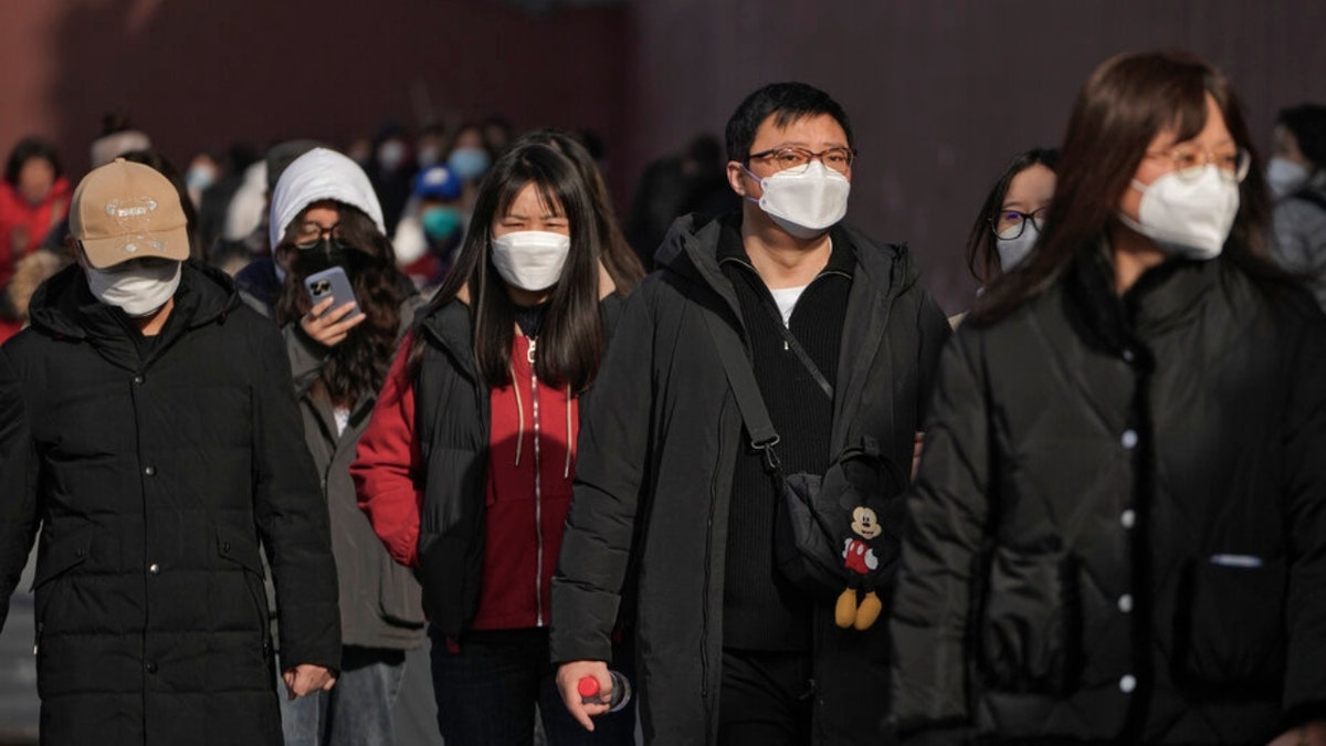 People wearing face masks walk in Beijing