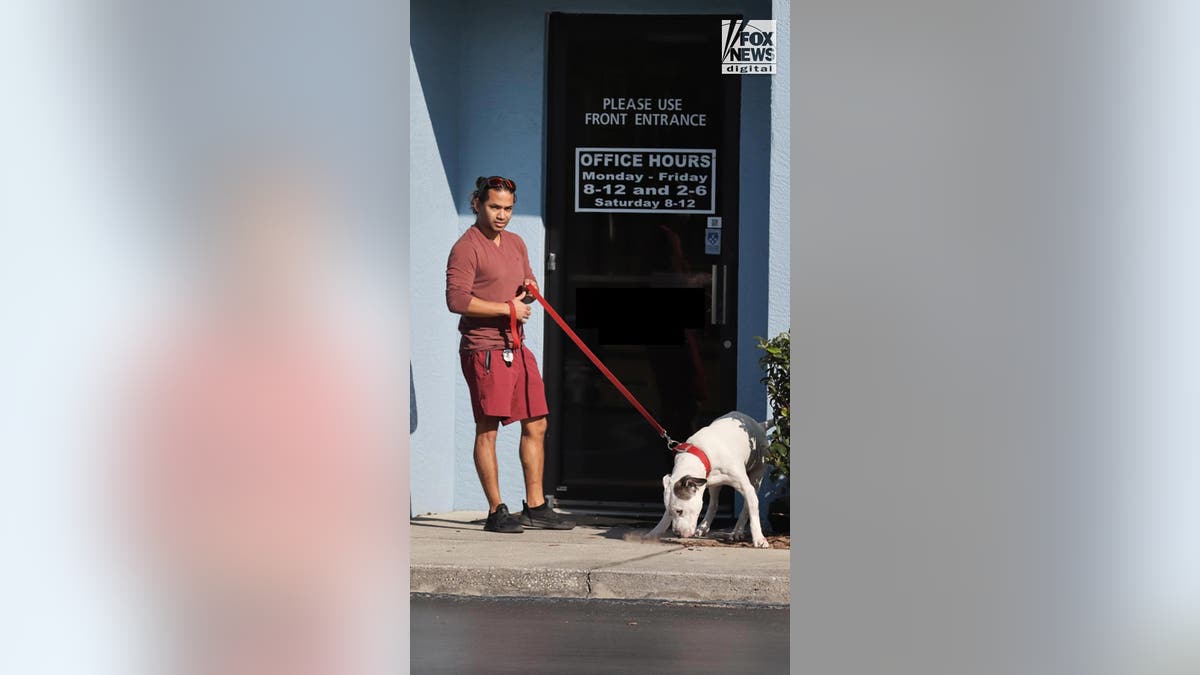 Man in shorts with a dog outside of an office