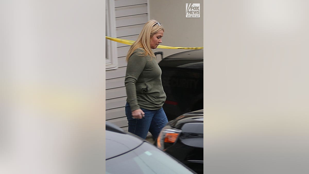 Woman in long-sleeved green t-shirt and jeans walks away from the house