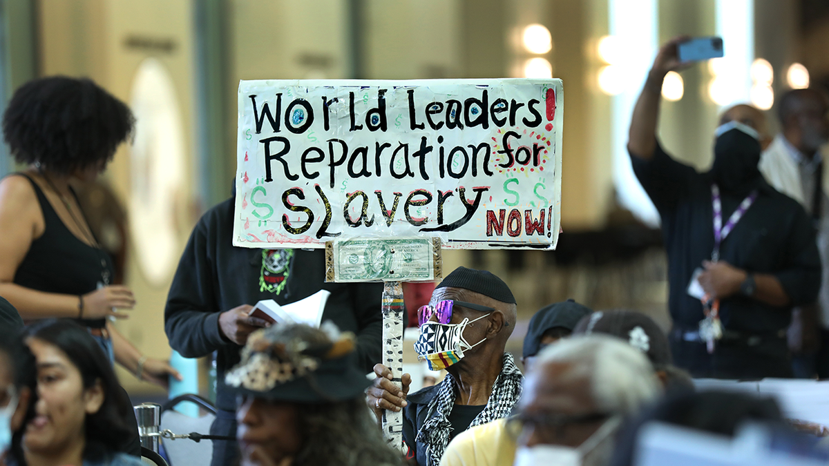Man holds up sign demanding reparations for slavery