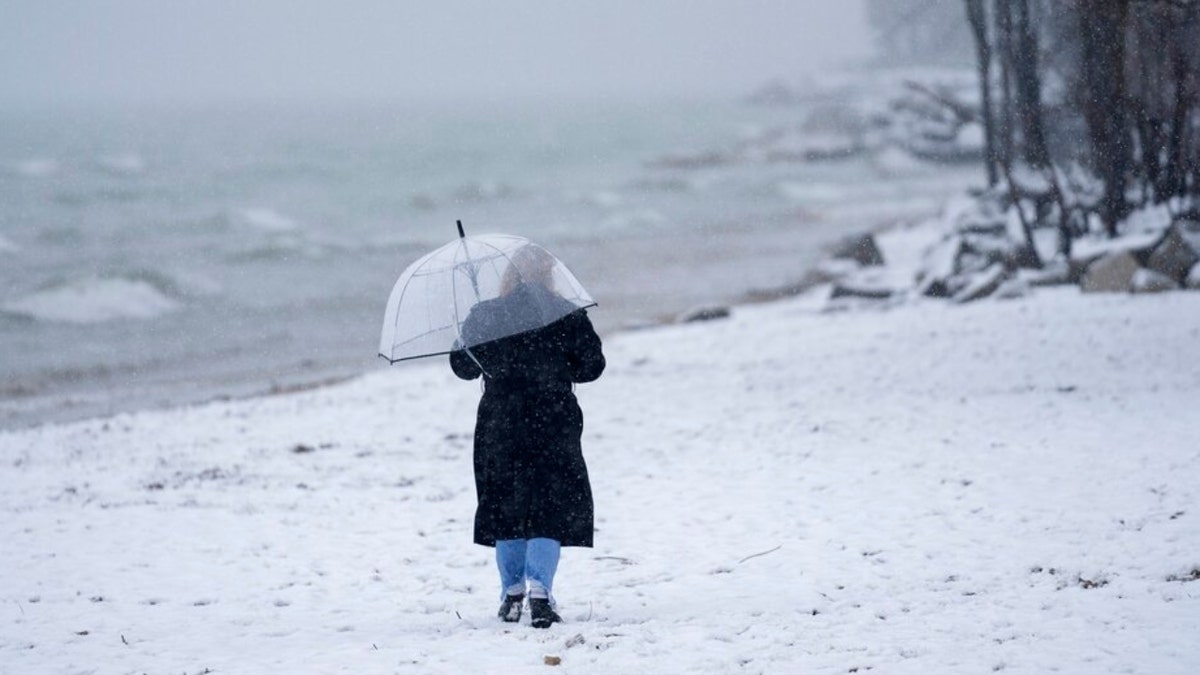 A person walks along North Shore Beach on a snowy day