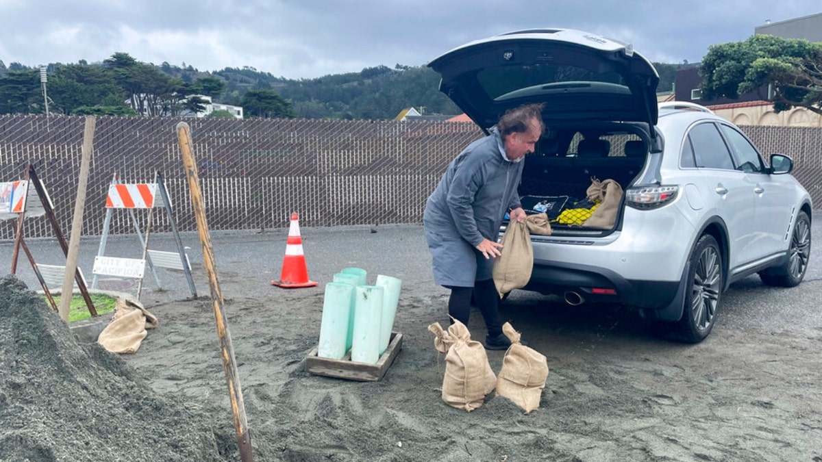 A man loads sandbags into a car in Pacifica, California