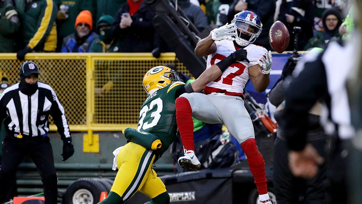 Green Bay Packers player breaks up a pass intended for a New York Giants player