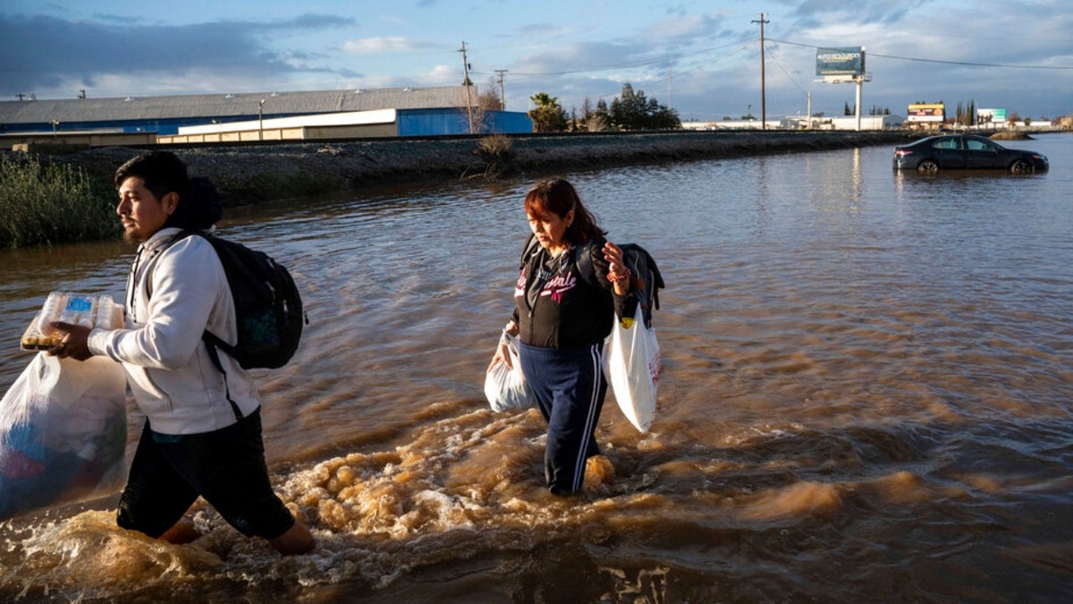 Merced residents carry belongings in floodwaters