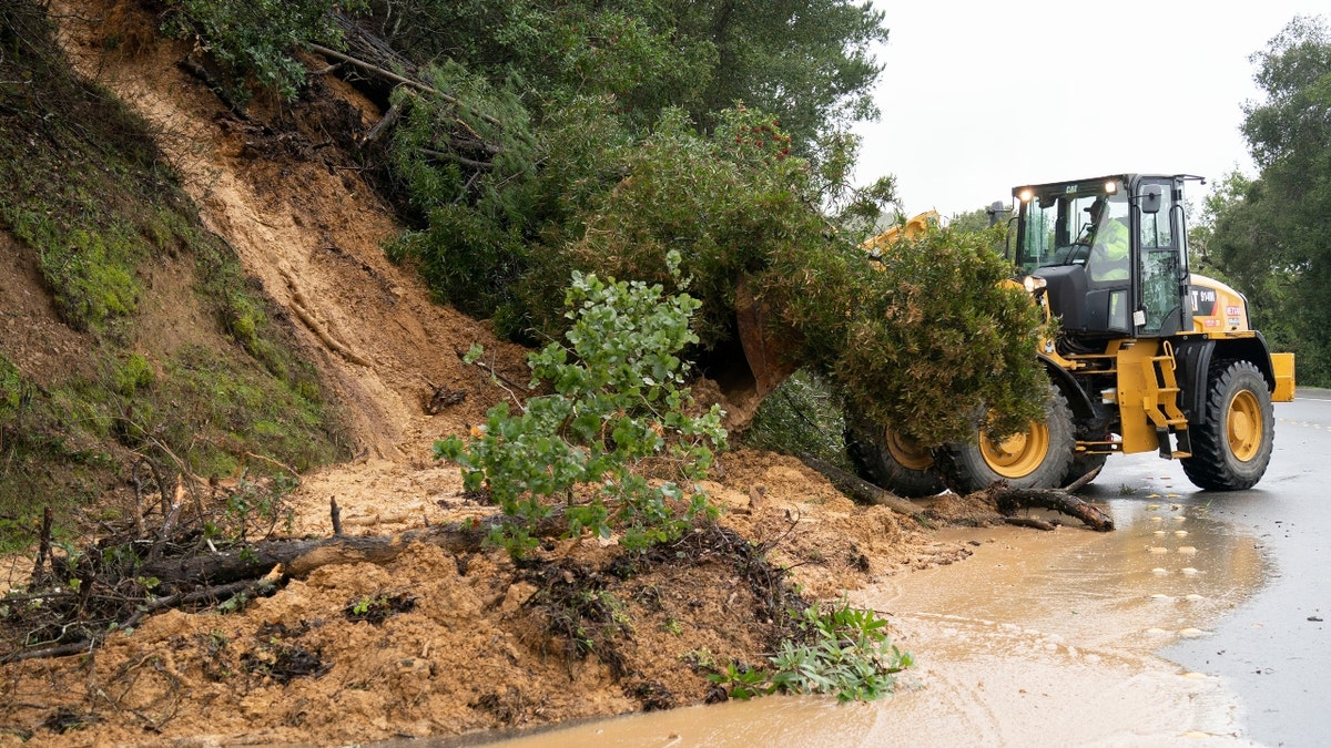 A worker operates a forklift to clear fallen trees and mud in San Mateo, Calif.