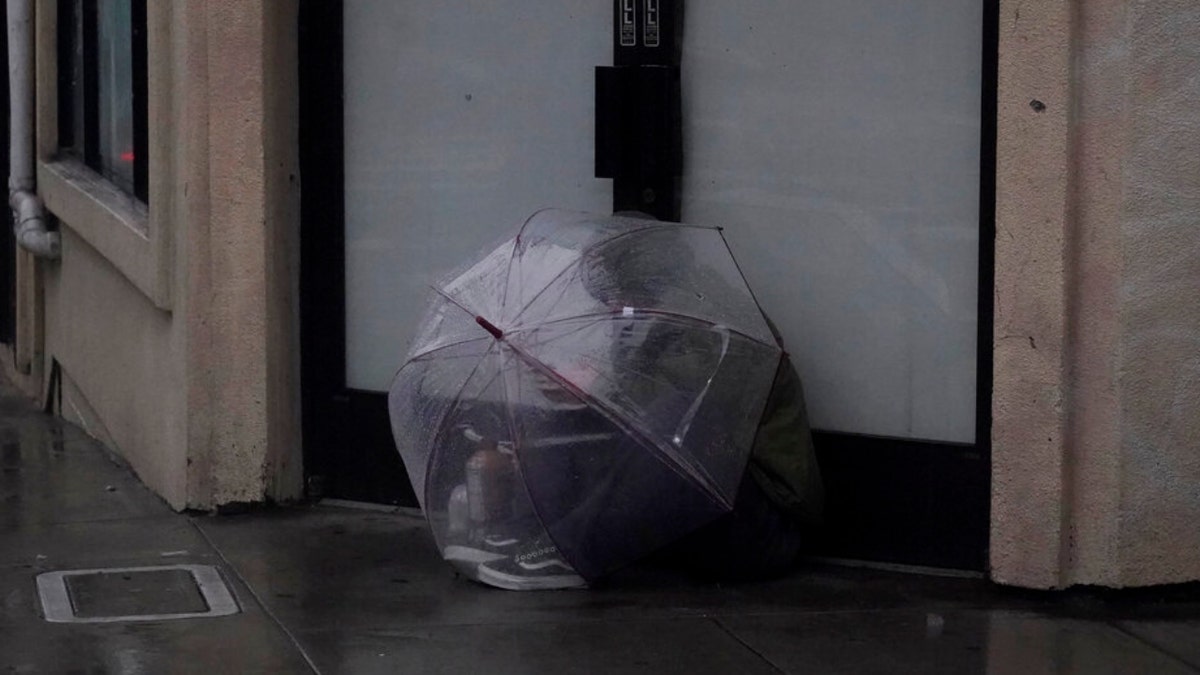 A person sits under an umbrella in San Francisco, Calif.