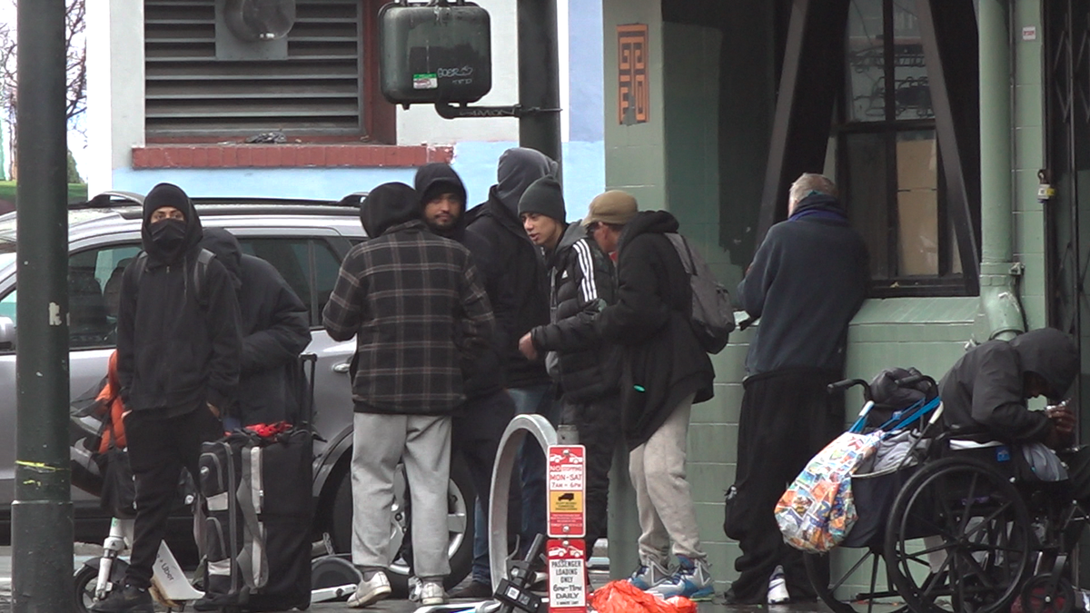 Drug dealers and drug users huddled on a street corner
