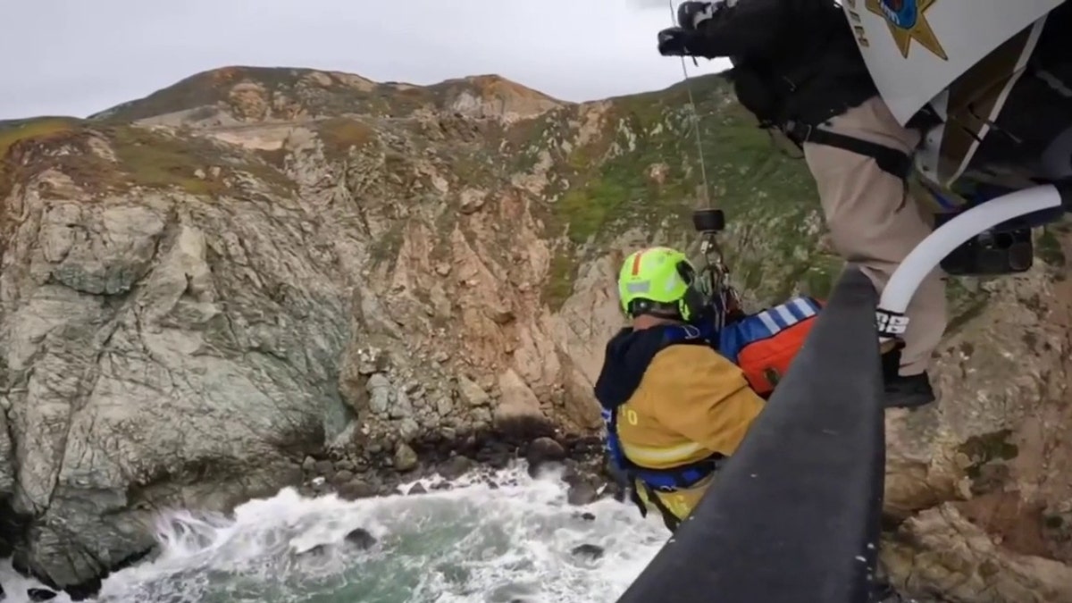 A firefighter hangs off the slide of a CHP helicopter