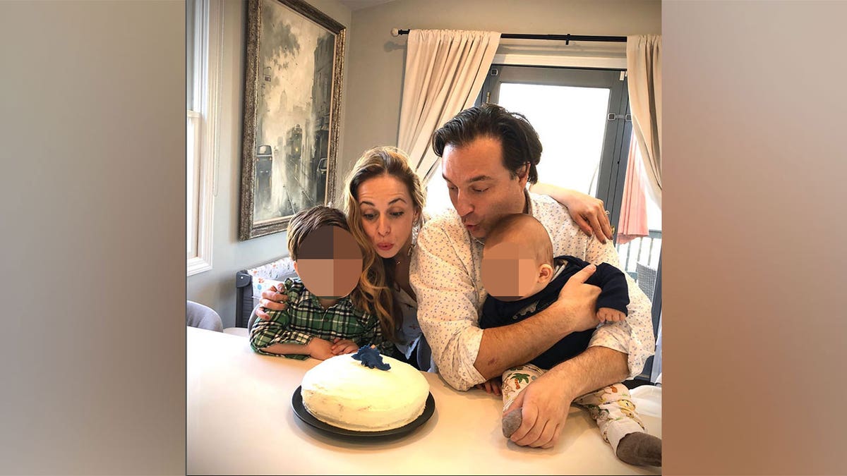 Ana and Brian hold their children and blow out birthday candles