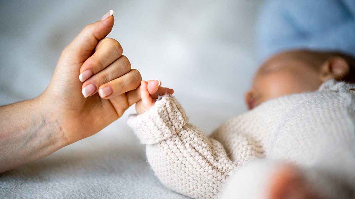 baby holding mom's finger