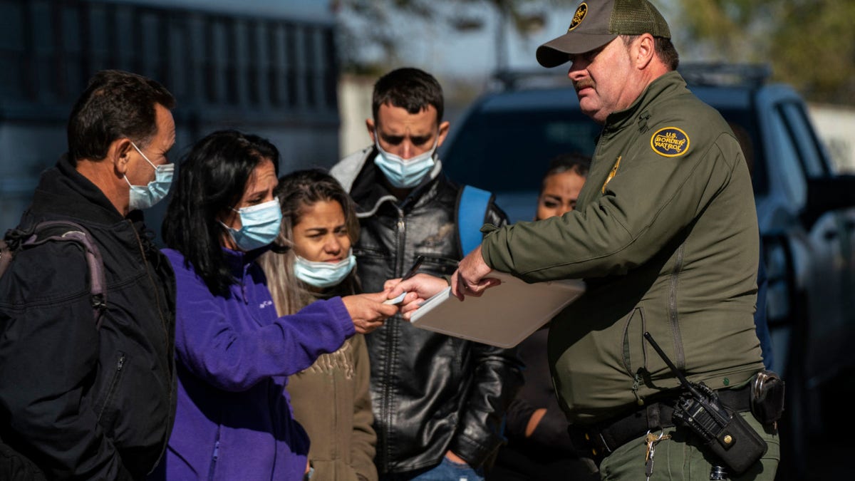 Migrants wait for their turn to have a Border Patrol agent write down their information in Eagle Pass, Texas on December 20, 2022