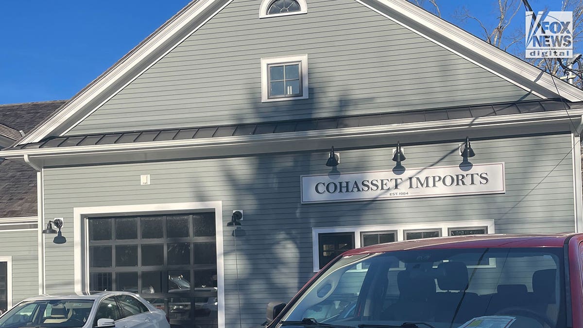 Business building painted gray and a red car parked out front