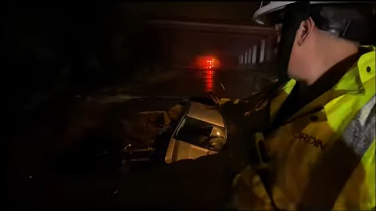 firefighter pointing at care in sinkhole