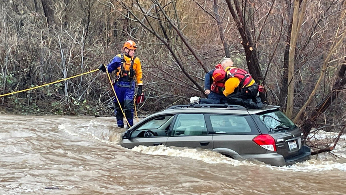 Rescue team saving man from car in floodwaters