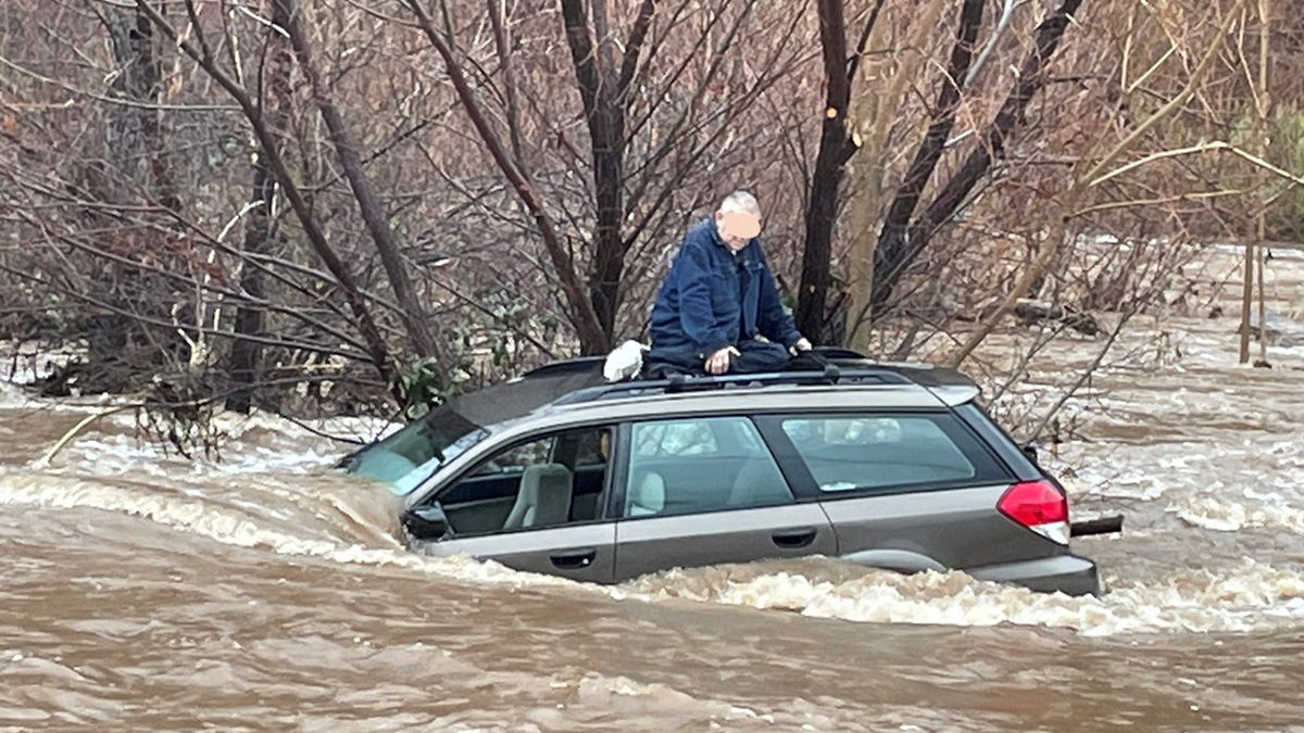 Man on roof of car during flood