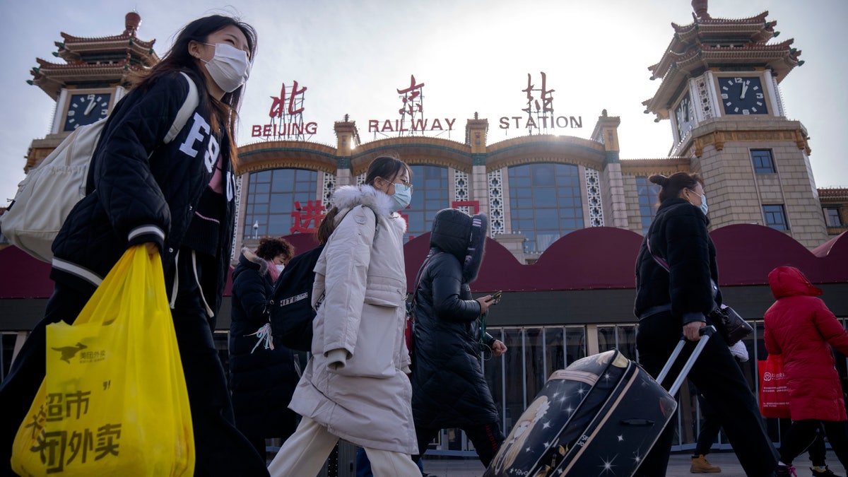 People walking by the Beijing Railway Station wearing face masks