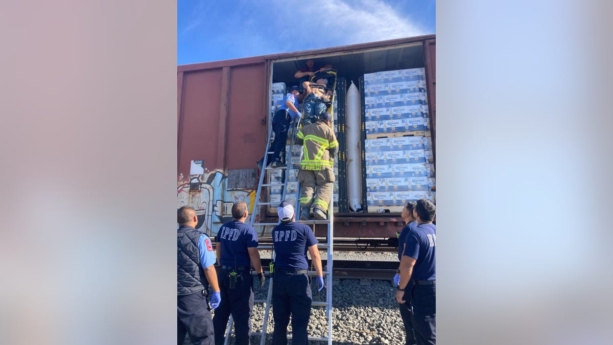 Firefighters pull migrants from a rail car carrying cases of Corona Extra beer