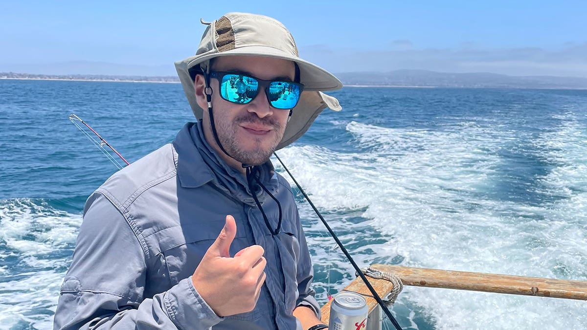 Elliot Blair smiles with thumb up on boat