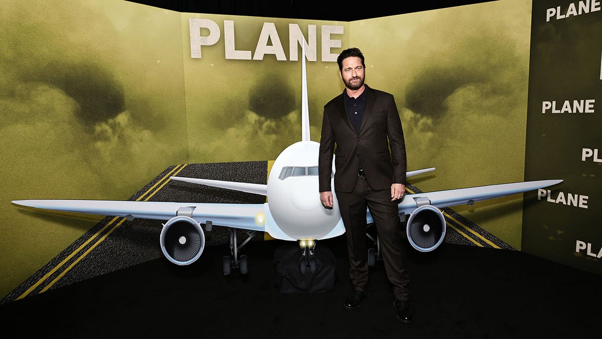 Gerard Butler in front of a poster for "Plane."