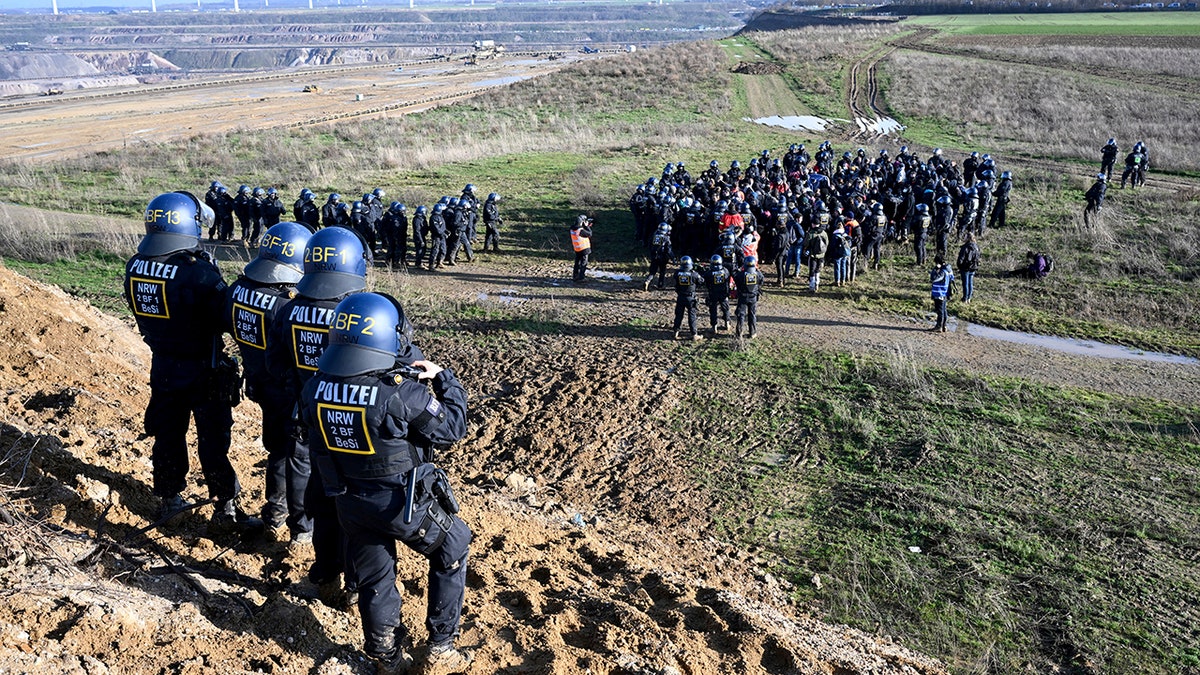 police looking out from hill at coal mine protesters