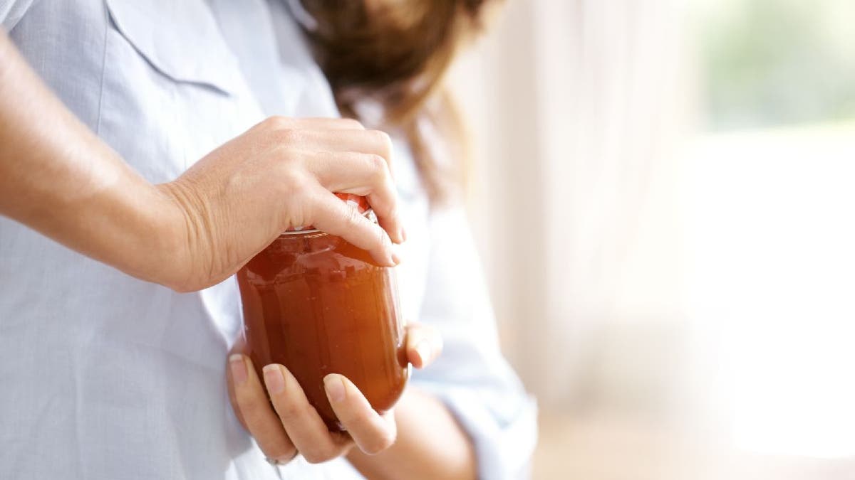 Woman struggles to open jar