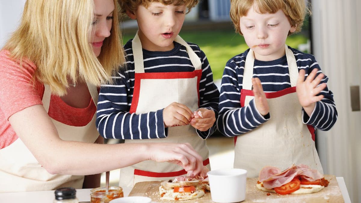 Woman makes pizza with twin boys