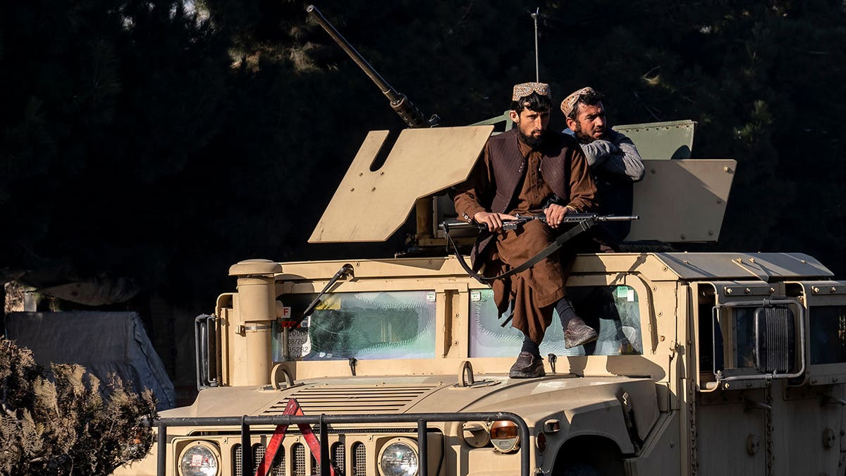 Taliban fighters sit atop of tank