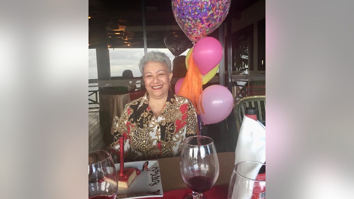 Maria Hernandez with balloons and wine at table