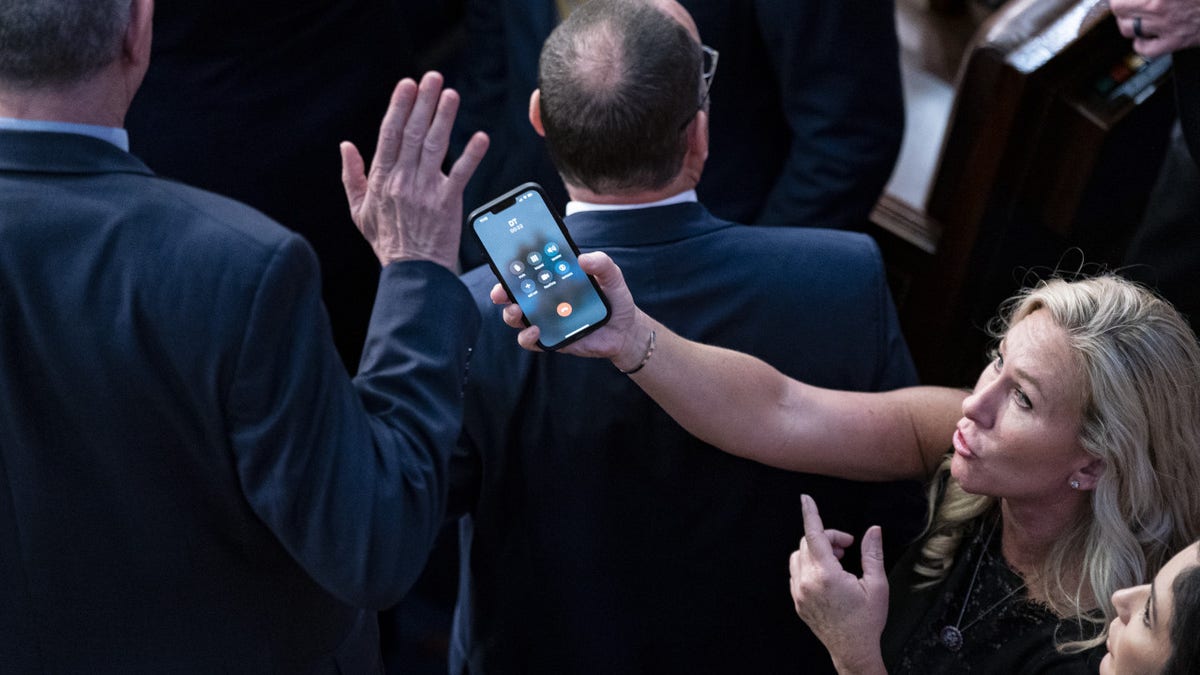 Representative Marjorie Taylor Greene, a Republican from Georgia, holds her smart phone with former US President Donald Trump on the line, as Representative Matt Rosendale, a Republican from Montana, waves it off