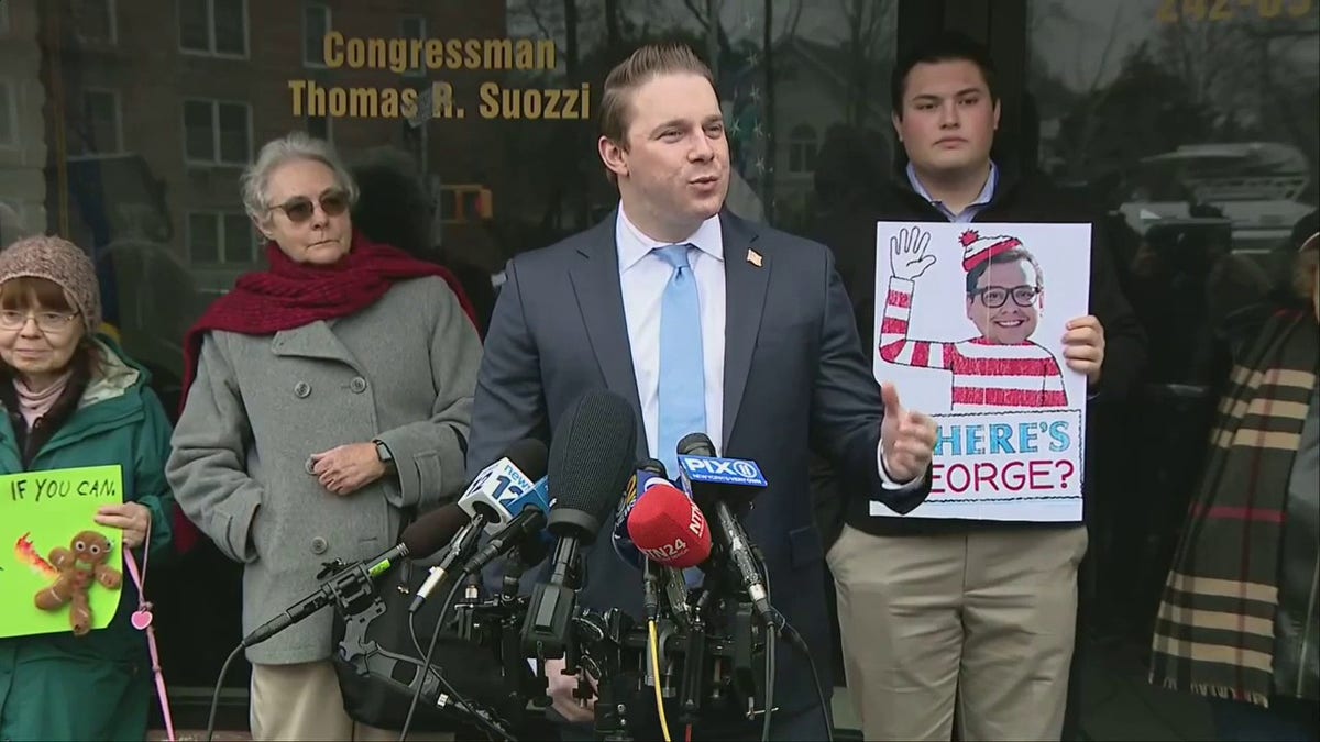 Josh Lafazan stands in front of a group of protesters, addressing reporters