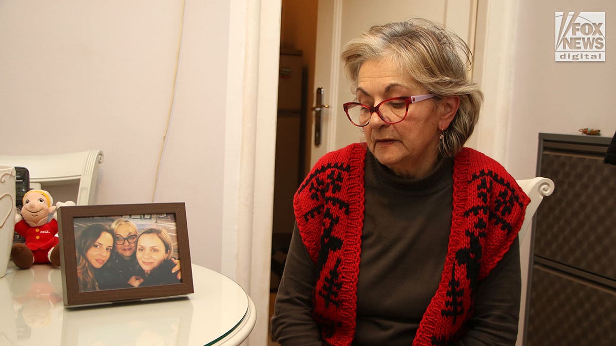 Woman in glasses looks at a framed photograph