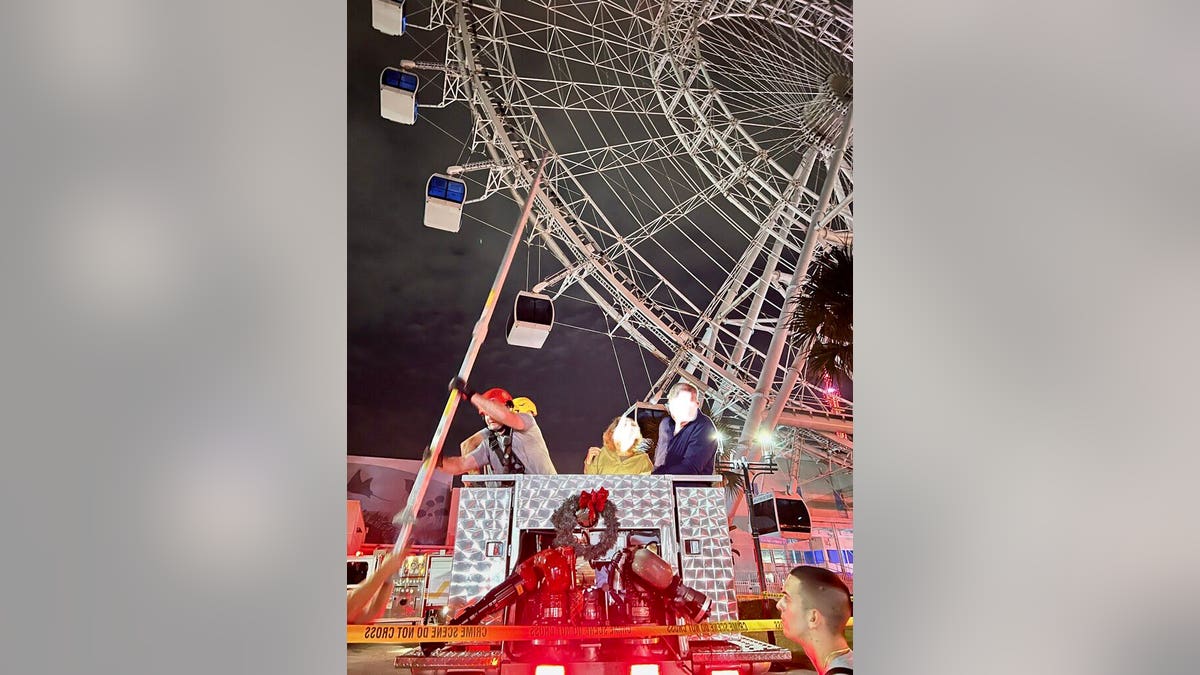 Firefighters manually turn Ferris wheel